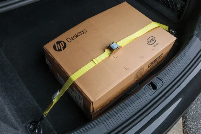 HP desktop box in a car trunk with a yellow strap