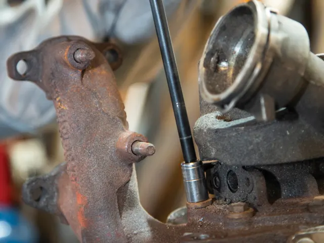 Close-up of a mechanical component with rust and a tool inserted