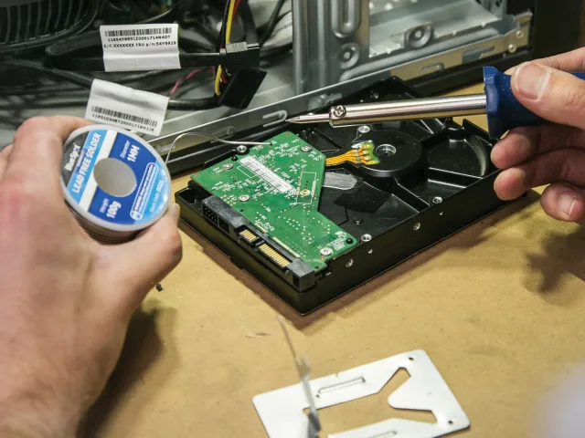 Person repairing a computer with tools and components on a table