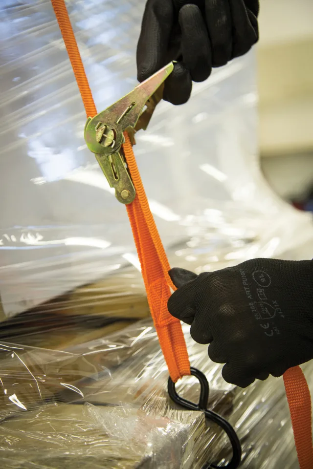 Person cutting orange strap with pliers on a reflective surface