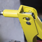 Yellow spray gun in use on a gray surface