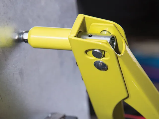 Yellow spray gun in use on a gray surface