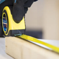 Person measuring a wooden block with a tape measure on a blurred background