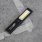 Black flashlight with visible brand name on a gray concrete surface