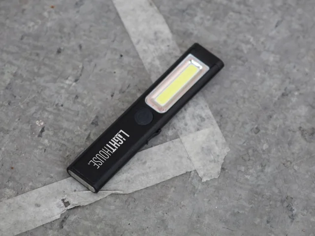 Black flashlight with visible brand name on a gray concrete surface