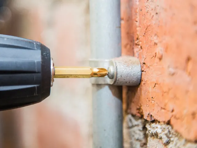 Drill bit attached to a drill bit adapter, drilling into a brick wall.