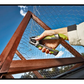 Person using a tool to work on a wooden frame with chicken wire against a blue sky.