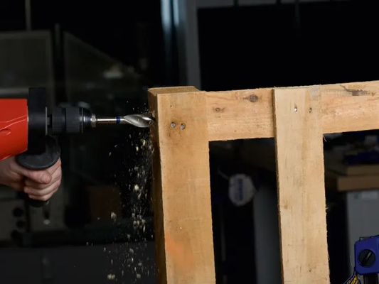 Drilling into a wooden pallet with a power drill