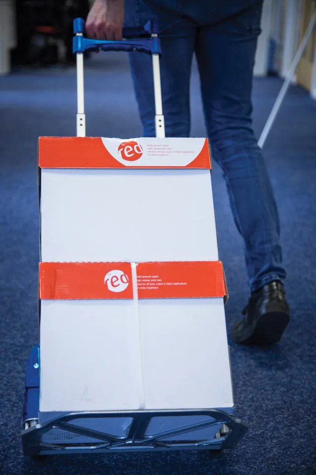 Person pushing a folding cart with 'tec' branding on a blue floor.
