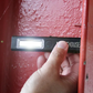 Hand holding a flashlight against a red door