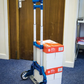 Blue and white dolly with stacked boxes against a wooden door.
