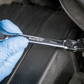 Person wearing blue gloves holding a BlueSpot wrench on a dark surface