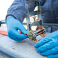 Person wearing blue gloves using a gold tool on a concrete surface
