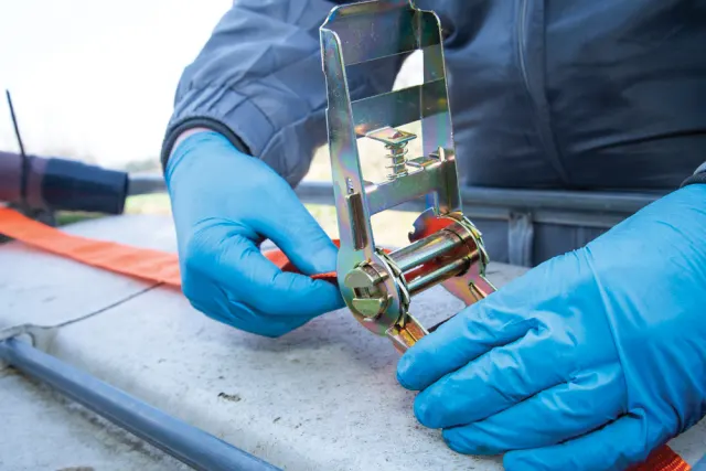 Person wearing blue gloves using a gold tool on a concrete surface